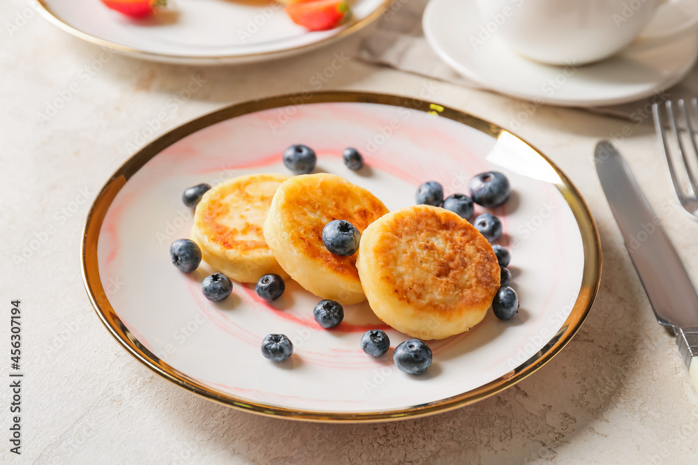 Plate with cottage cheese pancakes and blueberry on light background, closeup