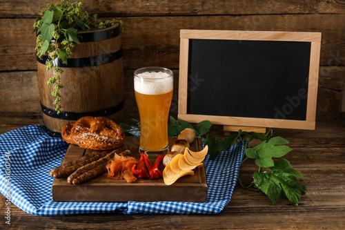 Composition with fresh beer and blank chalkboard on wooden background. Oktoberfest celebration