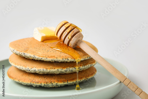 Plate of tasty pancakes with honey and butter on light background, closeup