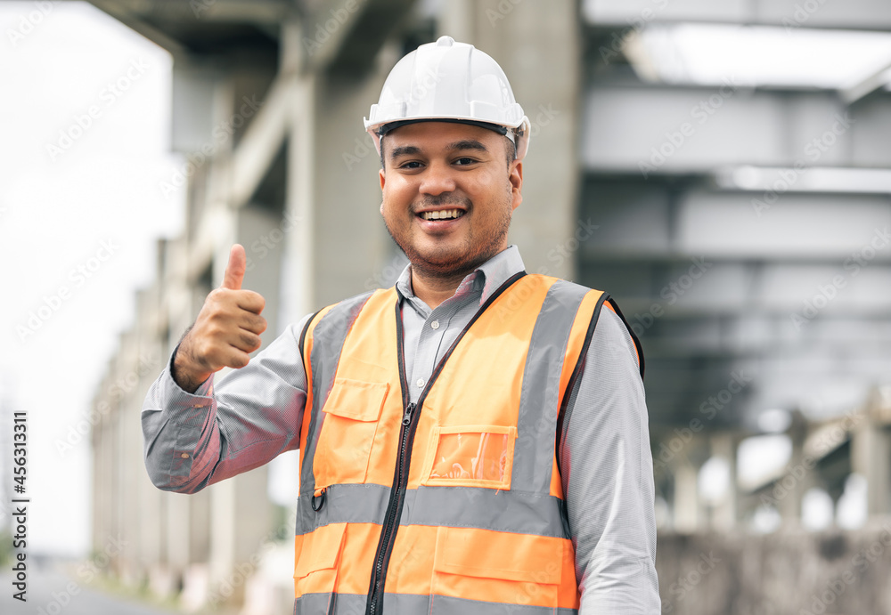 Asian engineer handsome man or architect looking construction with white safety helmet in construction site. Standing at highway concrete road site Showing thumbs up. Asian engineer handsome man or architect looking construction with white safety helmet in construction site. Standing at highway concrete road site Showing thumbs up.