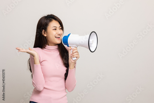 Shout out loud with megaphone. Young beautiful asian woman woman announces with a voice about promotions and advertisements for products at a discounted price. Shopping and fashion concept.