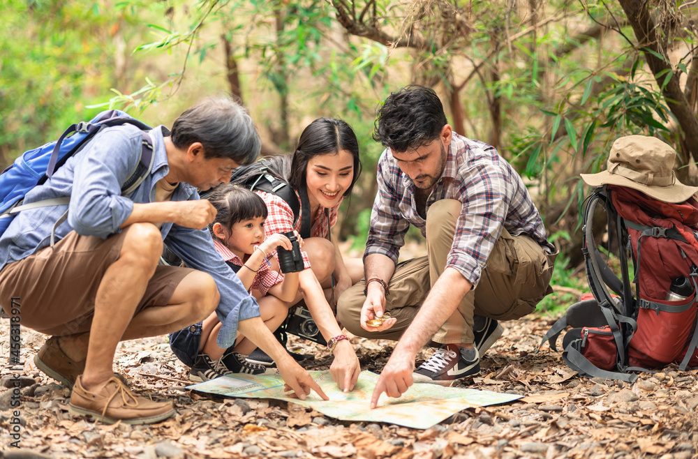 A group of young Asians are planning and looking at maps for camping in the forest.Asian and caucasian are backpackers.Tourism, adventure and summer vacation concept