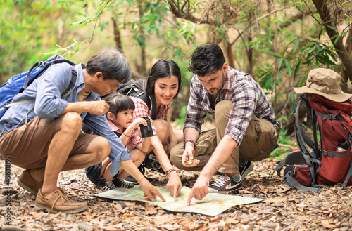 A group of young Asians are planning and looking at maps for camping in the forest.Asian and caucasian are backpackers.Tourism, adventure and summer vacation concept