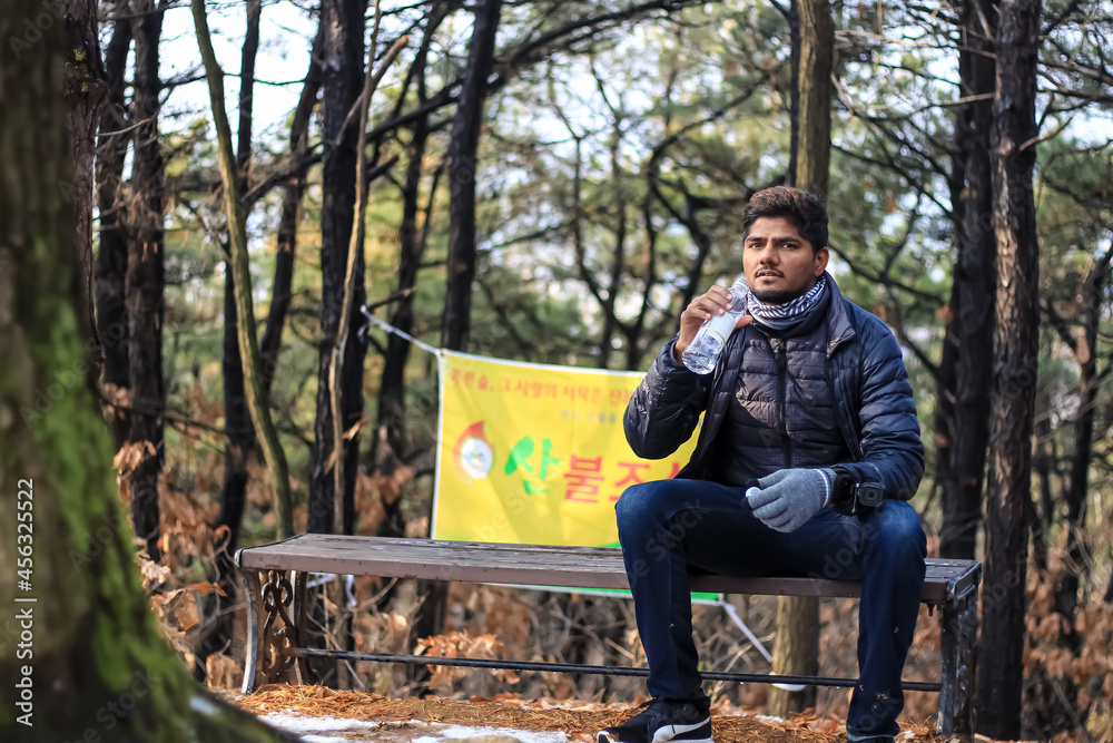 Fototapeta premium the person sitting on a bench in the park and drinking water