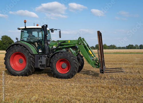 Strohernte - Traktor mit Frontlader beim Beladen eines Transportanh  ngers mit Strohballen.