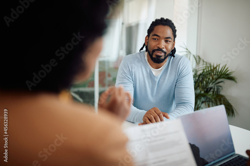 Smiling black businessman talks to colleagues during meeting in the office.