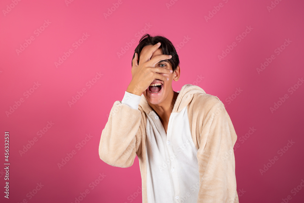 Young and handsome man in pajamas on a pink background. Emotions of guys.