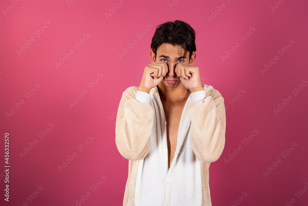 Young and handsome man in pajamas on a pink background. Emotions of guys. Young and handsome man in pajamas on a pink background. Emotions of guys.
