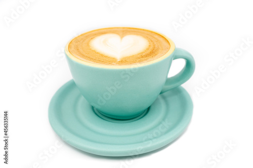 Close-up of cyan coffee cup, filled with coffee with milk foam and heart-shaped decoration. White background