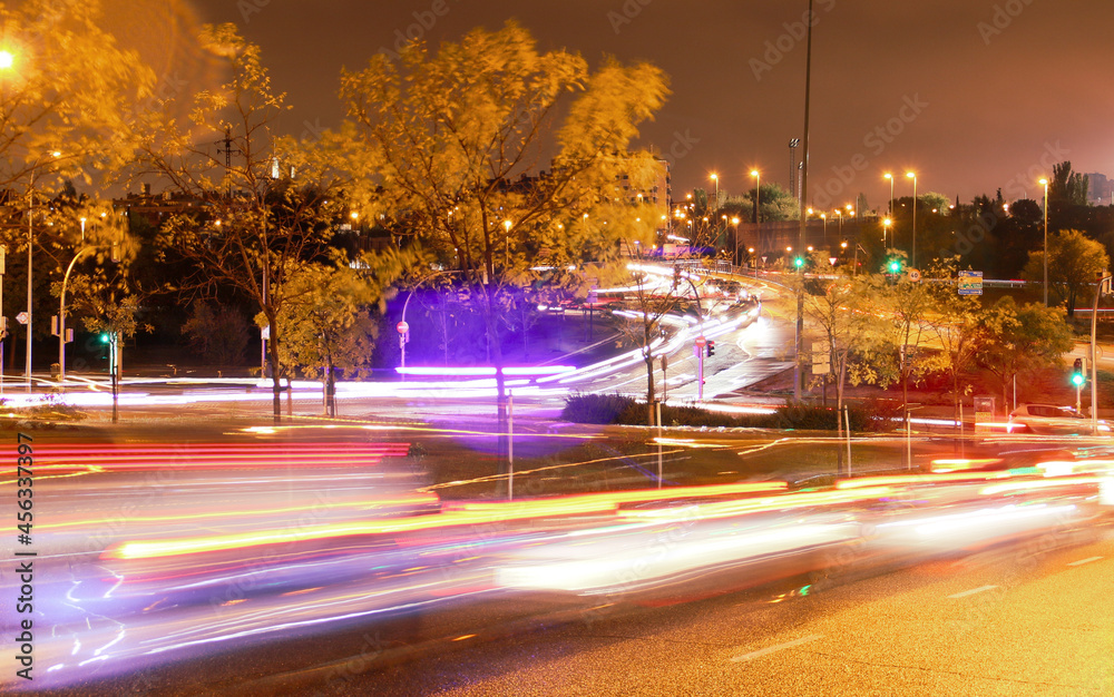 Tráfico nocturno en la avenida Montecarmelo en Madrid, España. Luces en movimiento de los automóviles tras una foto de exposición larga, farolas y semáforos en una noche lluviosa.