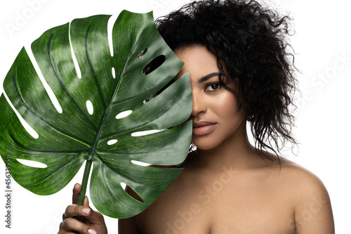 Beautiful black woman with a smooth skin holding green tropical leaf