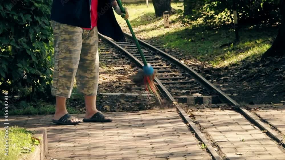 a man sweeps the pedestrian paths in the park during the day a man sweeps the pedestrian paths in the park during the day