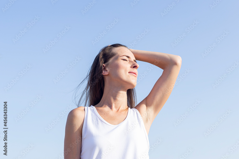 Young woman on a sunny day against the backdrop of a clear blue sky