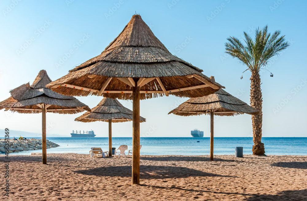 Sandy and sunny beach of the Red Sea with sunshades, chairs and deck-chairs for happy vacation after travel restrictions due to epidemic illness, Red Sea, Middle East