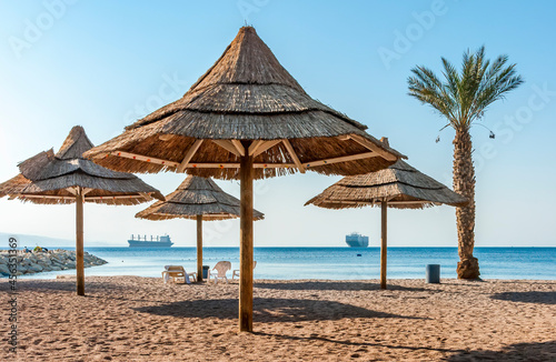 Fototapeta Naklejka Na Ścianę i Meble -  Sandy and sunny beach of the Red Sea with sunshades, chairs and deck-chairs for happy vacation after travel restrictions due to epidemic illness, Red Sea, Middle East