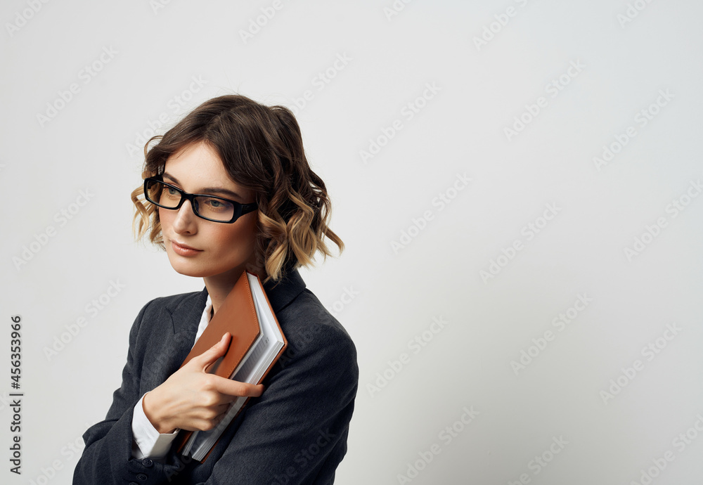 woman in business suit notebook in hand light background