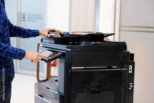 Businessmen press button on the panel for using photocopier or printer for printout and scanning document paper at office.