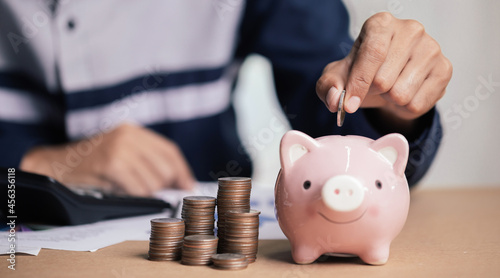 Fényképezés Man hand putting money coin into piggy for saving money wealth and financial concept