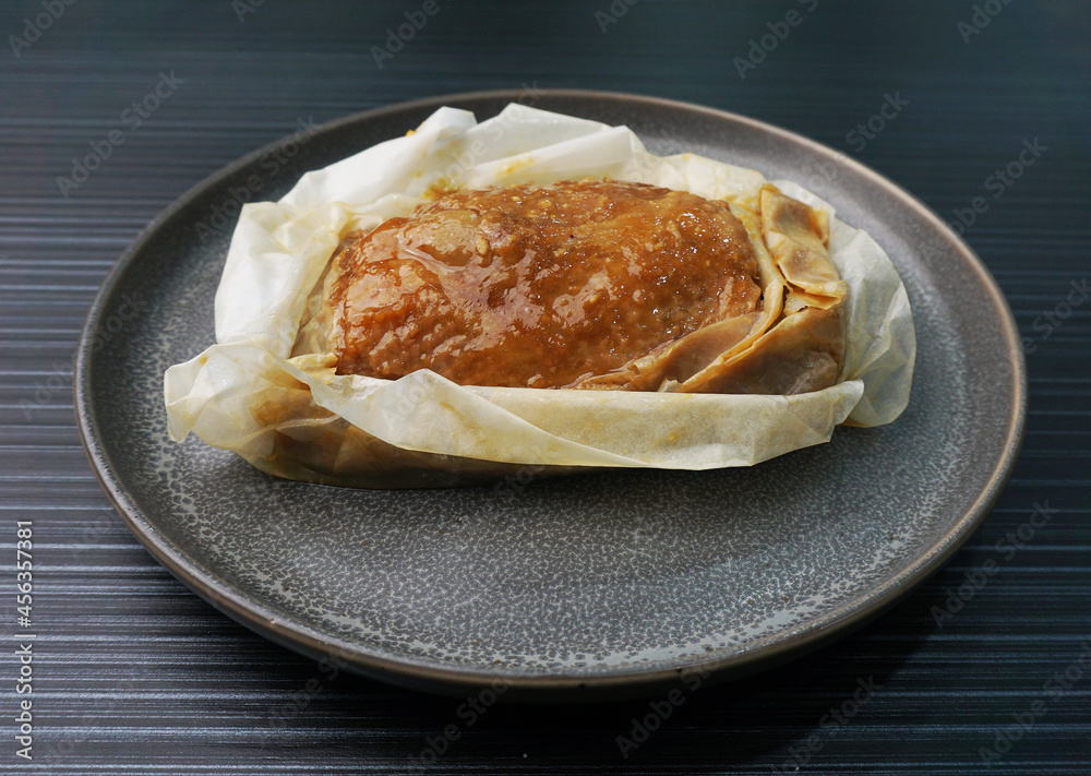 baked handmade paper wrapped chicken meat with herbal dark soy sauce on dark grey wood background dim sum menu baked handmade paper wrapped chicken meat with herbal dark soy sauce on dark grey wood background dim sum menu