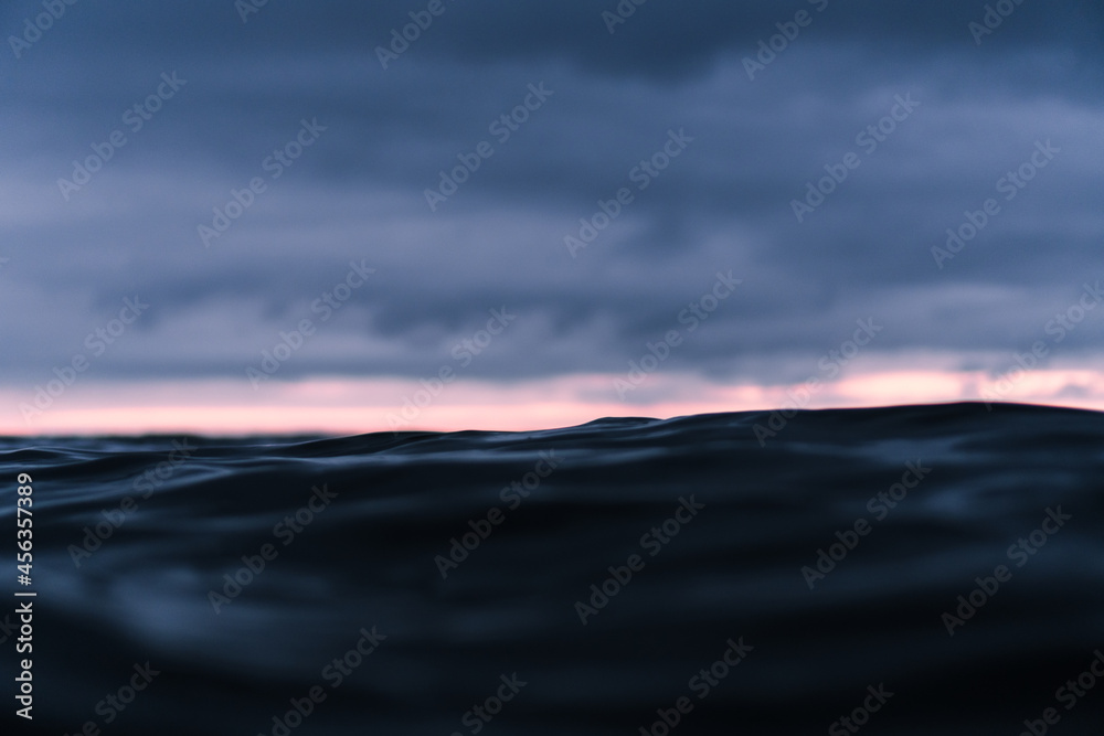 Cloudy sunset over the dark ocean with a bright stripe over the horizon