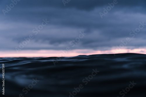 Cloudy sunset over the dark ocean with a bright stripe over the horizon