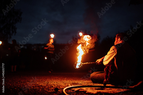 a dangerous and beautiful fireshow in the dark. artists in costumes of mythological creatures hold burning staffs and fans in their hands. juggling with fire