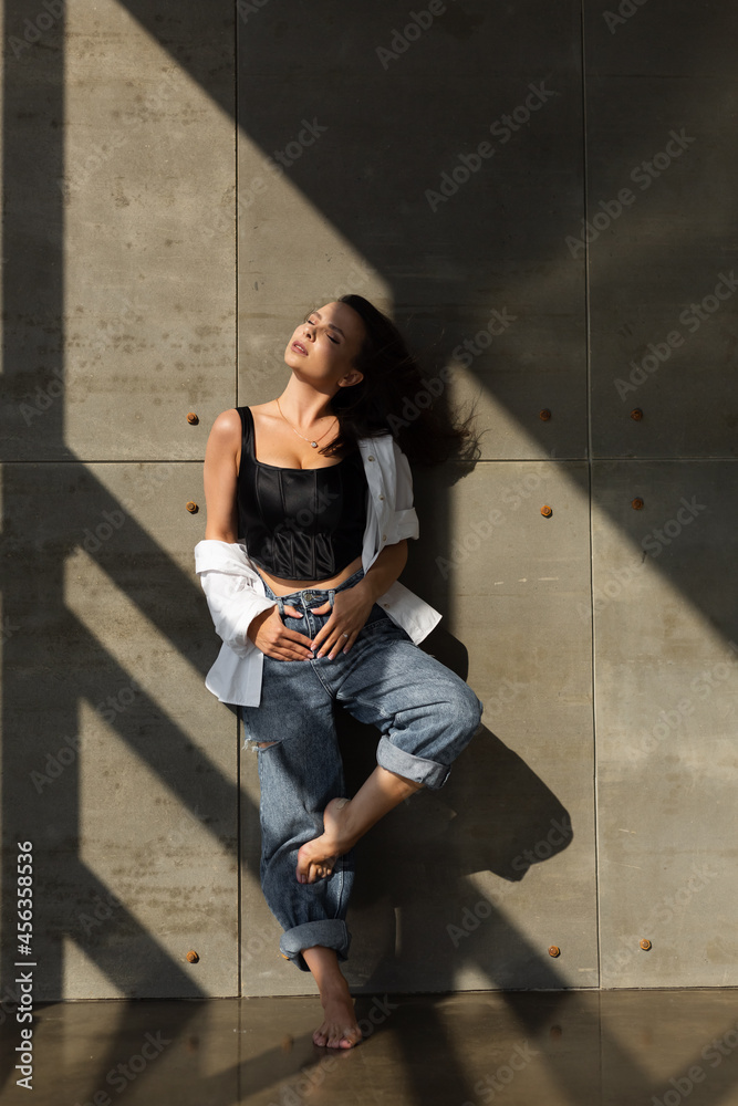 Pretty young woman with big breast posing in studio, by steel wall on background, wearing jeans and white shirt, natural warm sunset light Pretty young woman with big breast posing in studio, by steel wall on background, wearing jeans and white shirt, natural warm sunset light