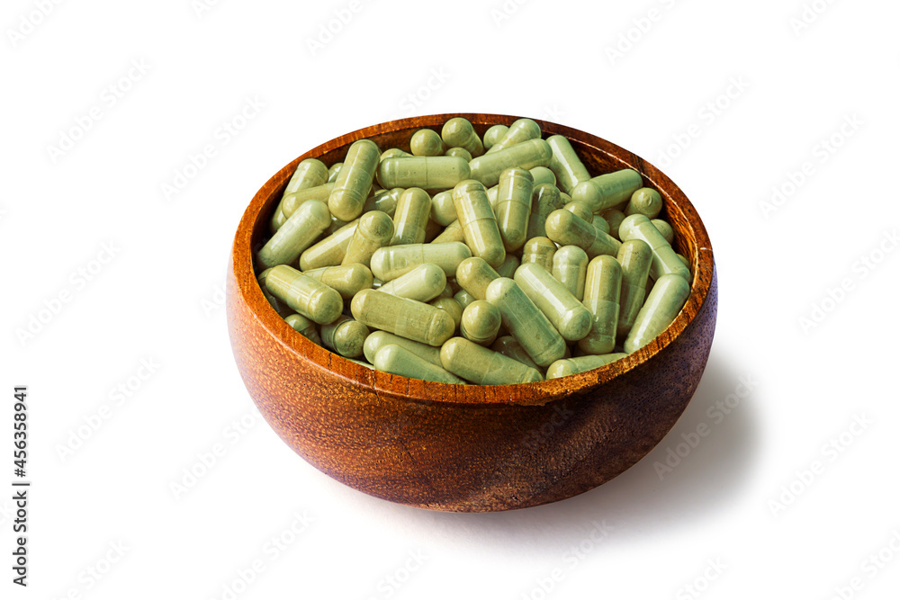 Andrographis paniculata capsules, wooden cup side view isolated on white background - Clipping path Andrographis paniculata capsules, wooden cup side view isolated on white background - Clipping path