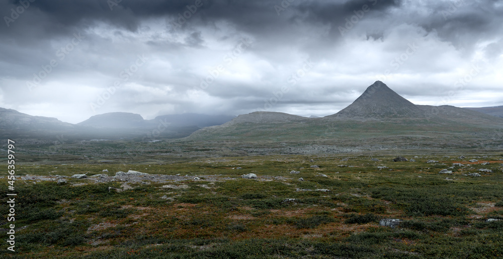 Epic panorama view of Mt Slugga in Swedish Lapland on a very cloudy day of arctic summer. Dramatic weather and landscape of arctic wilderness. Backpacking in Stora Sjofallet National Park.