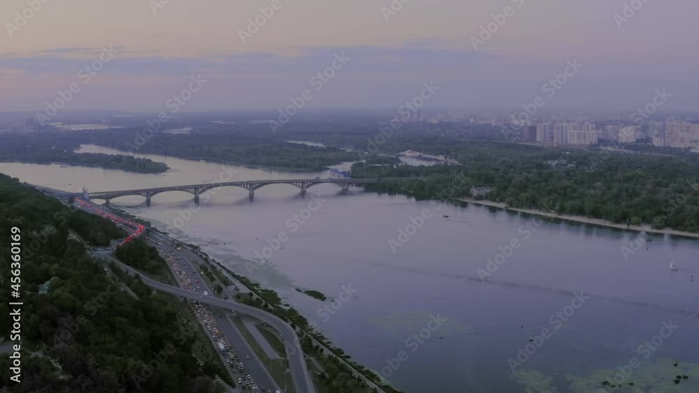 Bird's eye view of the Dnieper river with a bridge in the city of Kiev at sunset. A long bridge for car traffic runs across the Dnieper. Quiet smooth surface of the Dnieper at sunset. Bird's eye view of the Dnieper river with a bridge in the city of Kiev at sunset. A long bridge for car traffic runs across the Dnieper. Quiet smooth surface of the Dnieper at sunset.