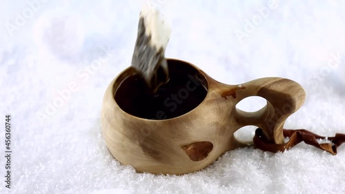 Kuksa. A tea in a Finnish wooden cup. Traditional Finnish wooden cup in the snow. Boiling water jet. The hand removes a tea bag from the cup. High quality FullHD footage