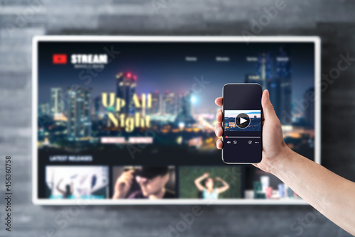 Movie stream with tv and phone. Watching on demand (VOD) series mockup with smart television and cellphone. Man using remote control video player app in smartphone. Streaming service subscription. photo