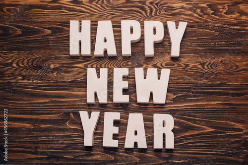 Christmas card with the inscription Happy New Year. White volumetric letters on a dark vintage wooden background. Minimalistic. Top view, close-up