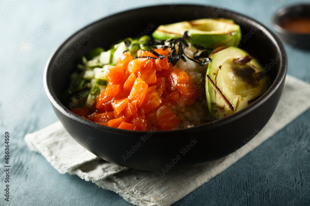 Healthy rice bowl with salmon and grilled avocado