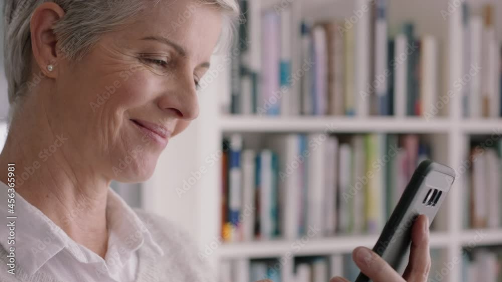 happy mature woman using smartphone texting browsing social media reading text messages enjoying digital communication on mobile phone 4k footage