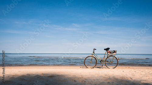 green vintage bicycle on white sand beach over blue sea and clear blue sky background, spring or summer holiday vacation concept.