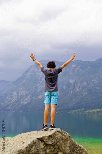 cute boy on the top of the rock in lake bohinj, slovenia