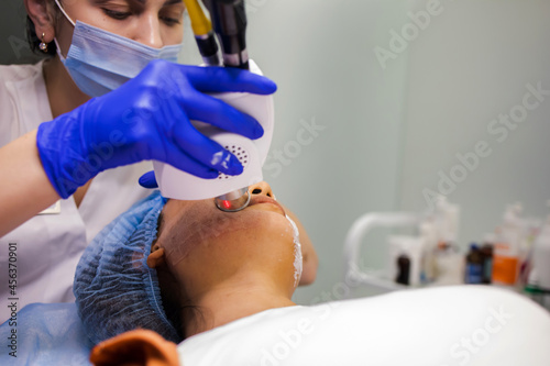 Asian Woman receiving laser and ultrasound facial treatment in a health resort center