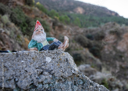 gnome lying on a stone and mountains in the background with vegetation photo