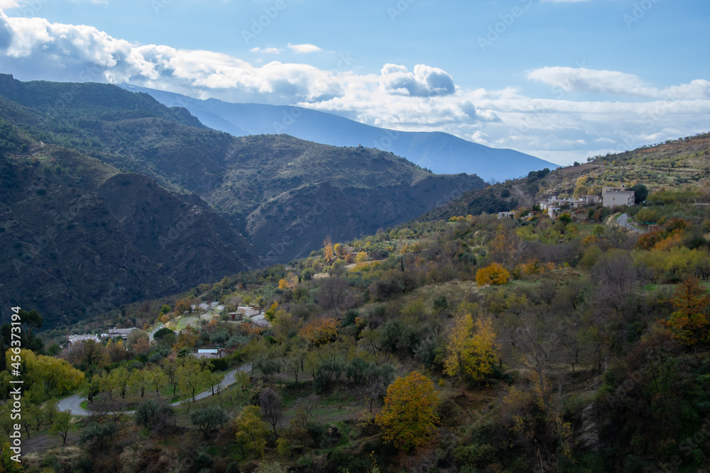 Autumn view of a panoramic view of the towns of Mecina and Mecinilla of La Taha in the Alpujarra, surrounded by a forest of trees with yellow, ocher and green leaves