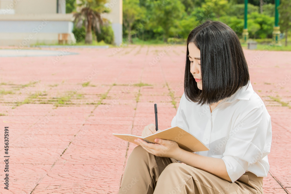Obraz premium a woman sitting and writing a notebook in the park