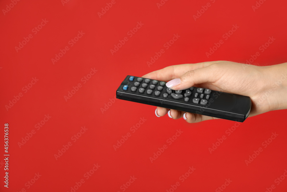 Woman holding remote control on red background, closeup Woman holding remote control on red background, closeup