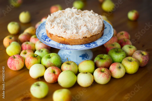 Apple pie with meringue on the top surrounded with green and red autumn apples