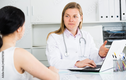 Female visitor consulting smiling woman doctor in hospital