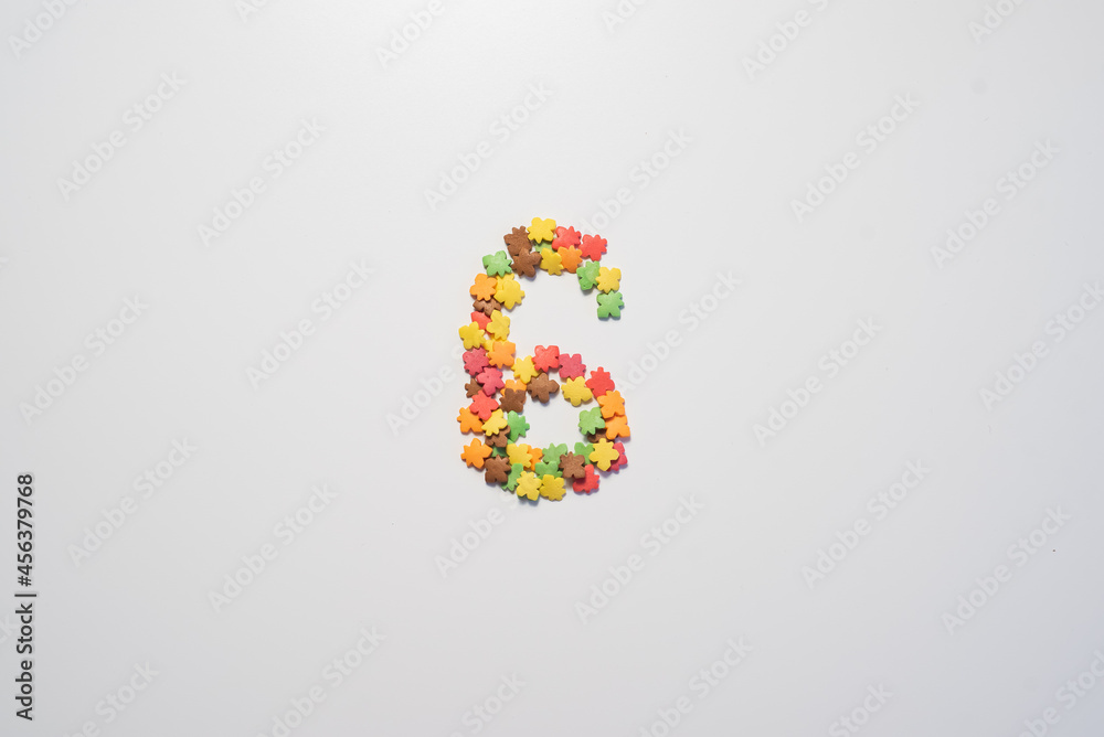 Number six from sweet pastry topping in the form of colorful foliage on a white background. Number six from sweet pastry topping in the form of colorful foliage on a white background.