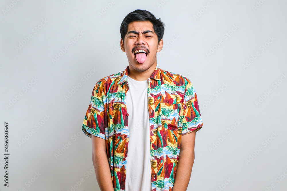 Young handsome asian boy wearing casual shirt sticking tongue out happy with funny expression. Young handsome asian boy wearing casual shirt sticking tongue out happy with funny expression.