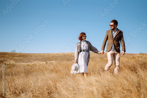 Young couple in love walking outdoors on a sunny day. The man gently hugs the woman. Love story. Autumn style.