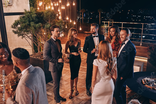 Fotografie Group of people in formalwear communicating and smiling while spending time on l