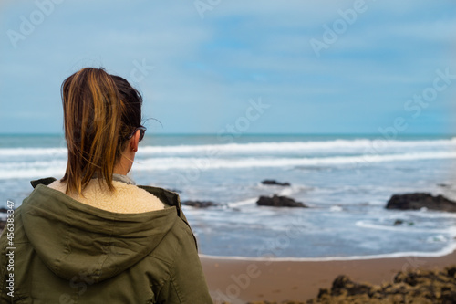 a girl enjoys on the beach in front of the sea while pointing and opening her arms for a healthy life full of peace and freedom