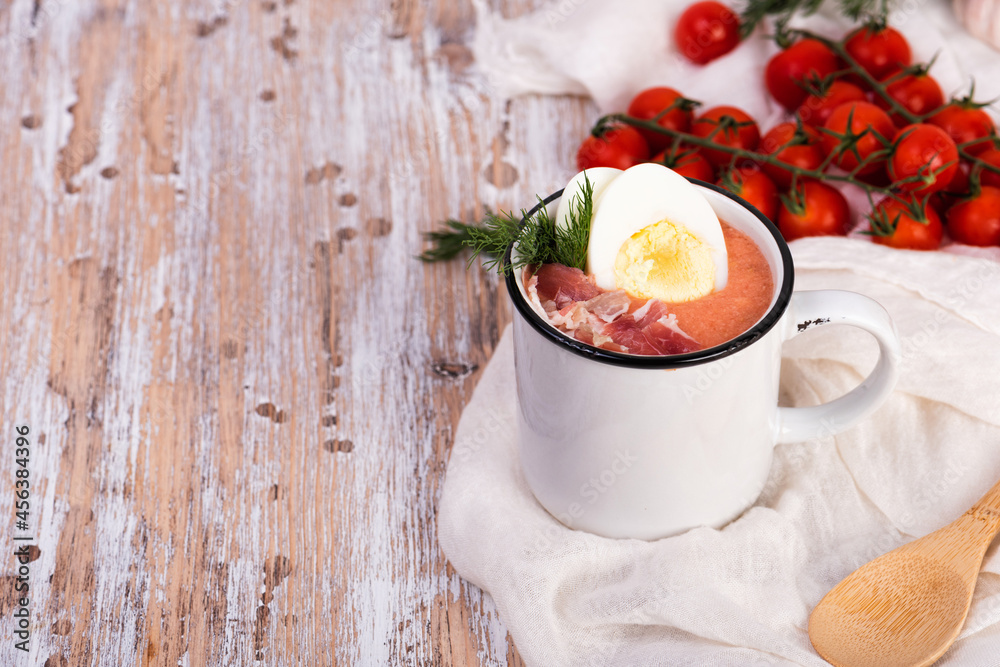 Spanish salmorejo cream soup with ham and egg on a wooden rustic table. Mugs of spicy tomato cold soup Spanish salmorejo cream soup with ham and egg on a wooden rustic table. Mugs of spicy tomato cold soup